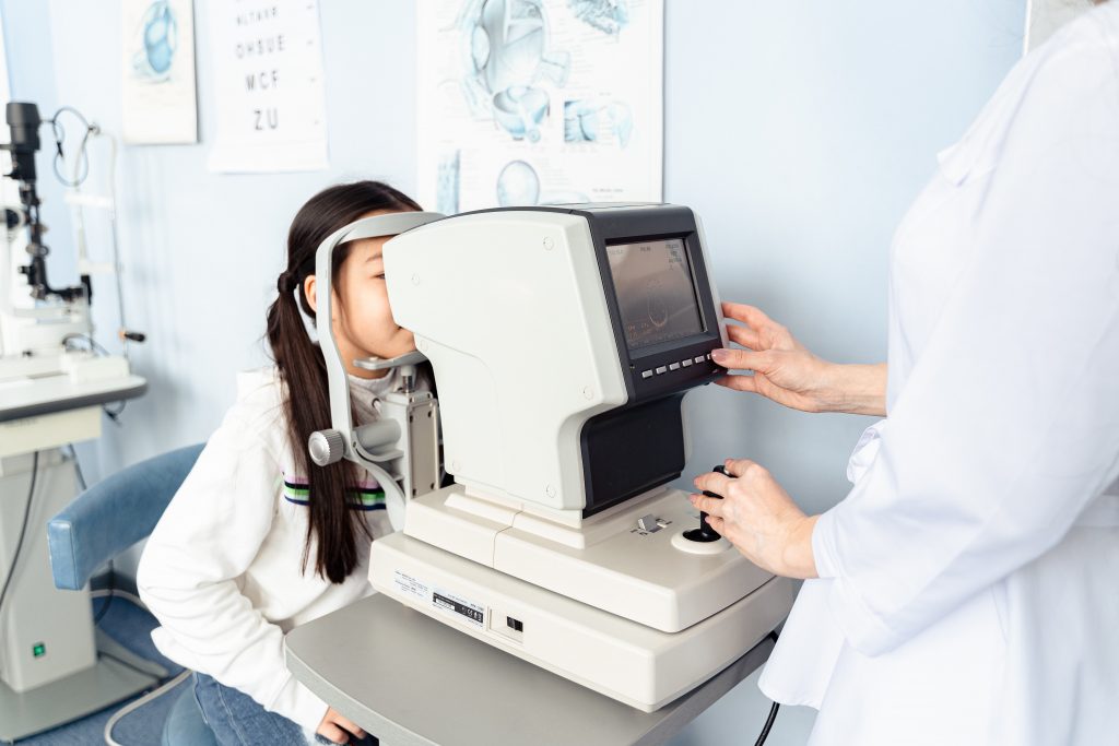 A young girl gets her eyes tested through a computer screen-like machine.