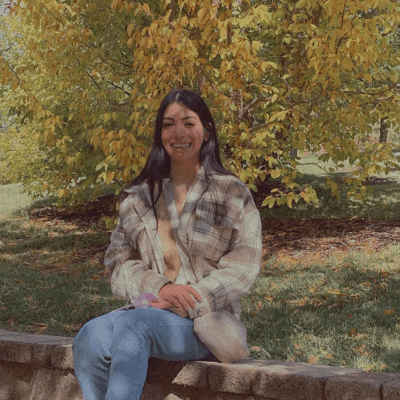 Myra sitting underneath a tree smiling